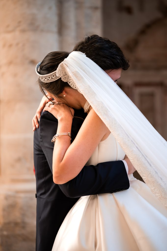 Emotional embrace between the bride and groom beneath a delicate lace veil at Monasterio de Piedra. Romantic editorial wedding photography captured in a historic Spanish monastery.