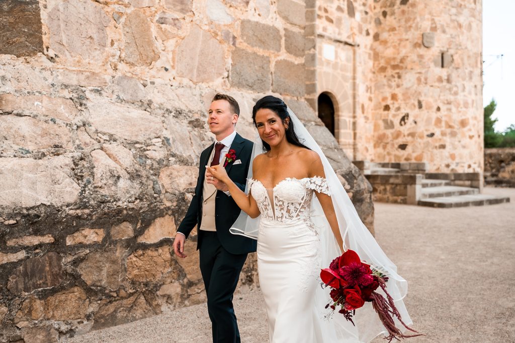 Novios paseando junto a los muros del Castillo de Guadamur, Toledo — destination wedding fotografiado por The Ro Wedding Photo